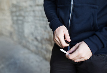 Image showing close up of addict hands with marijuana joint