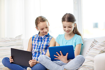 Image showing happy girls with tablet pc sitting on sofa at home