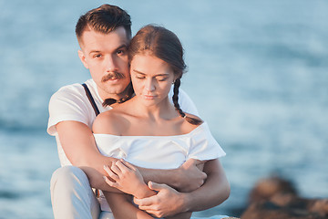 Image showing Happy young romantic couple relaxing on the beach and watching the sunset