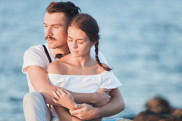 Image showing Happy young romantic couple relaxing on the beach and watching the sunset