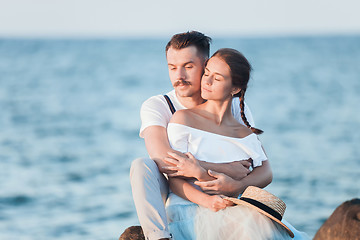 Image showing Happy young romantic couple relaxing on the beach and watching the sunset