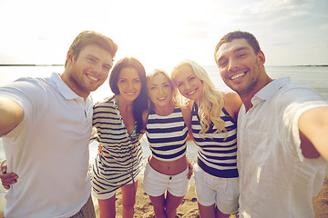 Image showing happy friends on beach and taking selfie