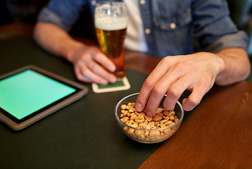 Image showing man with tablet pc, beer and peanuts at bar or pub