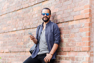 Image showing man with backpack texting on smartphone in city