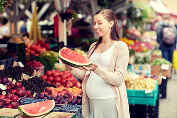 Image showing pregnant woman holding watermelon at street market