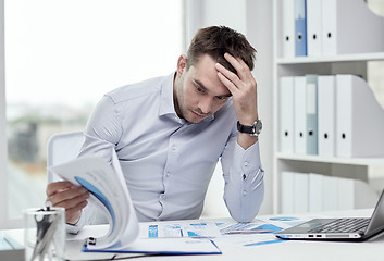 Image showing stressed businessman with papers at office