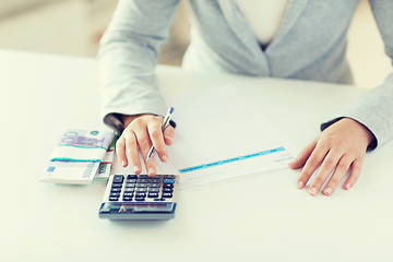 Image showing close up of hands counting money with calculator