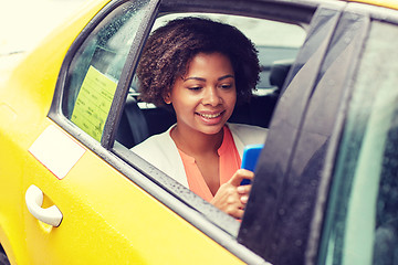 Image showing happy african woman texing on smartphone in taxi