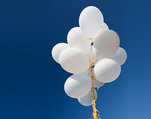 Image showing close up of white helium balloons in blue sky