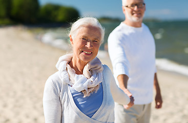 Image showing happy senior couple holding hands on summer beach