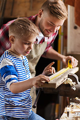 Image showing father and son with ruler measure wood at workshop