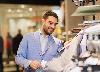 Image showing happy young man choosing clothes in clothing store