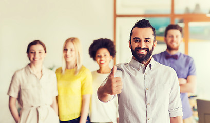 Image showing happy man showing thumbs up over team in office