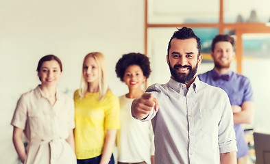 Image showing happy man pointing finger at you over office team