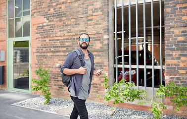 Image showing man with earphones and smartphone walking in city