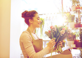 Image showing smiling florist woman making bunch at flower shop