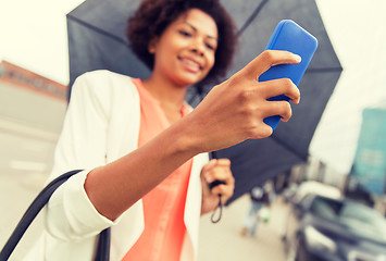 Image showing close up of woman with umbrella and smartphone