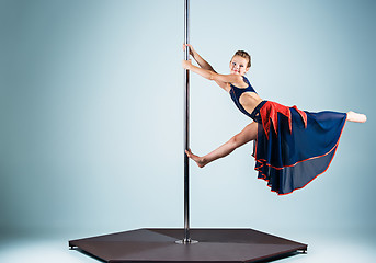 Image showing The strong and graceful young girl performing acrobatic exercises on pylon