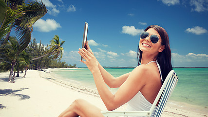 Image showing smiling woman with tablet pc sunbathing on beach