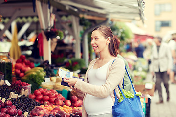 Image showing pregnant woman with wallet buying food at market