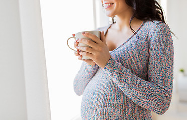 Image showing close up of pregnant woman with tea cup at window