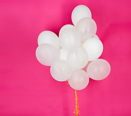 Image showing close up of white helium balloons over pink