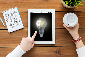 Image showing close up of woman with tablet pc on wooden table