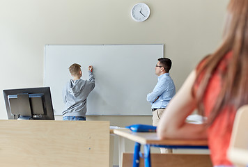 Image showing teacher and student writing on board at school