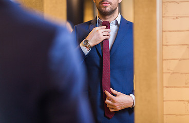 Image showing close up of man trying tie on at mirror