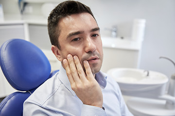 Image showing man having toothache and sitting on dental chair