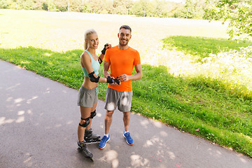 Image showing happy couple with roller skates riding outdoors