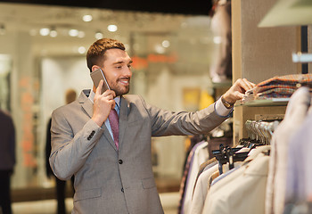 Image showing happy man calling on smartphone at clothing store