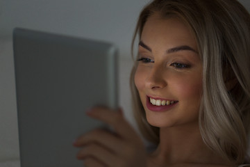 Image showing young woman with tablet pc in bed at night