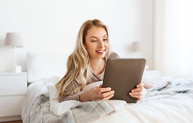 Image showing happy young woman with tablet pc in bed at home