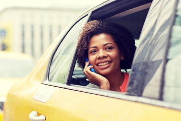 Image showing happy african woman calling on smartphone in taxi