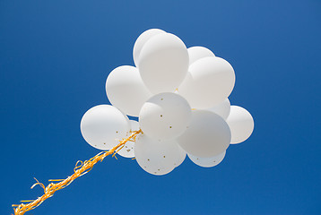 Image showing close up of white helium balloons in blue sky