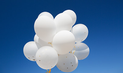 Image showing close up of white helium balloons in blue sky