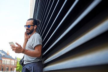 Image showing man with earphones and smartphone on city street