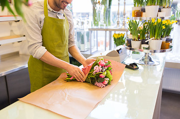 Image showing florist wrapping flowers in paper at flower shop