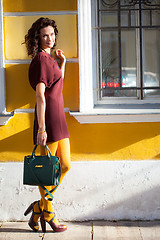 Image showing beautiful smiling woman in a burgundy dress with green handbag
