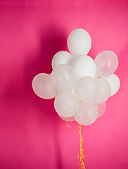 Image showing close up of white helium balloons over pink