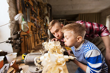 Image showing father and little son with wood plank at workshop