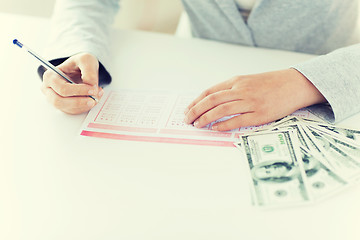 Image showing close up of hands with lottery ticket and money