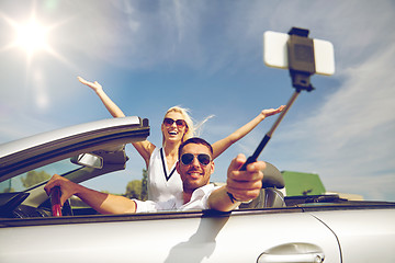 Image showing happy couple in car taking selfie with smartphone