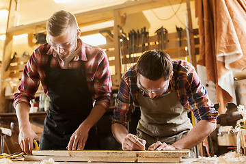 Image showing carpenters with ruler and wood plank at workshop