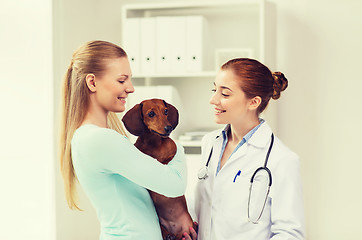 Image showing happy woman with dog and doctor at vet clinic