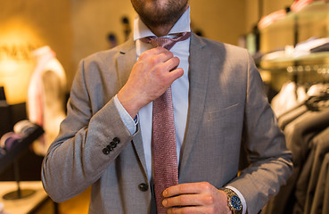 Image showing close up of man tying tie at clothing store mirror