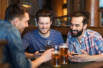 Image showing male friends with smartphones drinking beer at bar