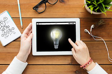 Image showing close up of woman with tablet pc on wooden table