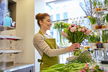 Image showing smiling florist woman making bunch at flower shop